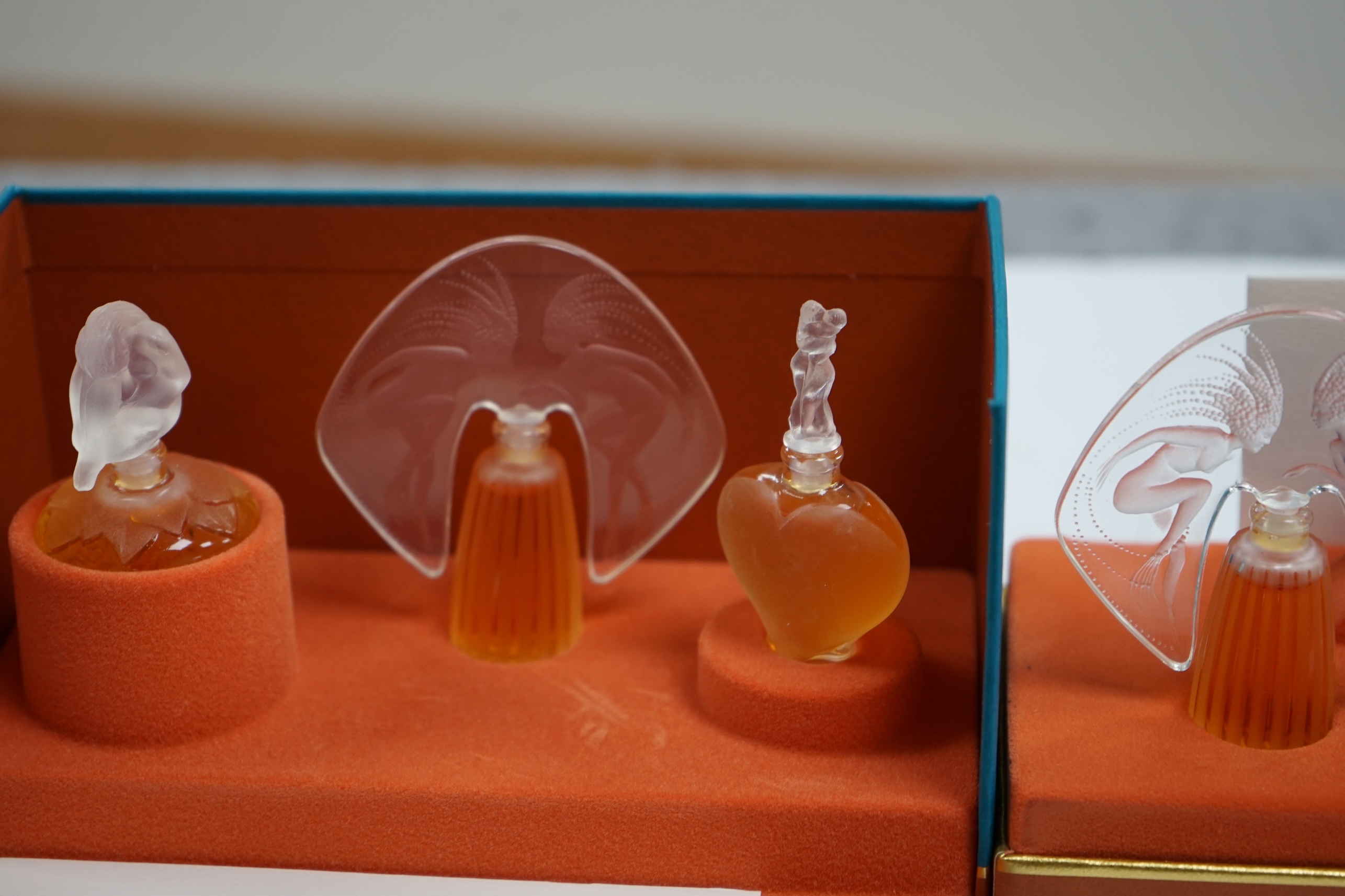 Two Lalique sets of three miniature perfume bottles. 'Les flacons miniatures' 1996-1997 and 1998-2000, boxed and sealed, tallest 7cm high. Condition - good